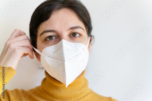 Portrait of caucasian woman with respiratory problems wearing preventive a face mask at home. Healthcare for young high risk patients with coronavirus. Covid 19 quarantine at home concept.