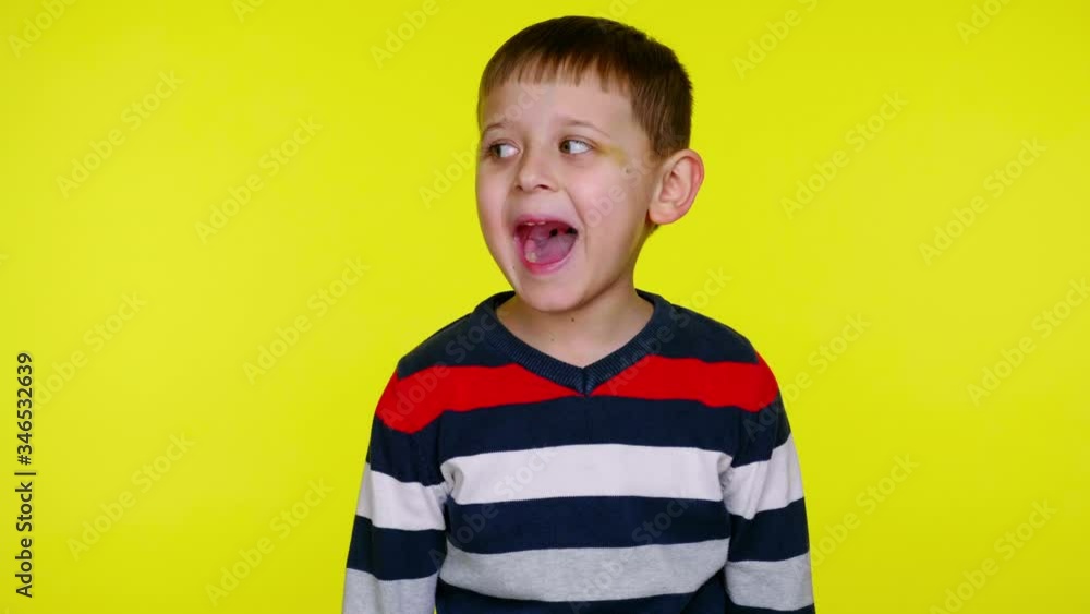 Little child boy in a colorful sweater screaming on a yellow background with copy space. Place for text or product. 4K slowmotion footage Little child boy in a colorful sweater screaming on a yellow background with copy space. Place for text or product. 4K slowmotion footage