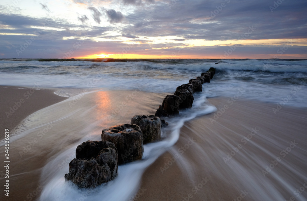 Morze Bałtyckie,wschód słońca,falochron na plaży w Kołobrzegu,Polska.