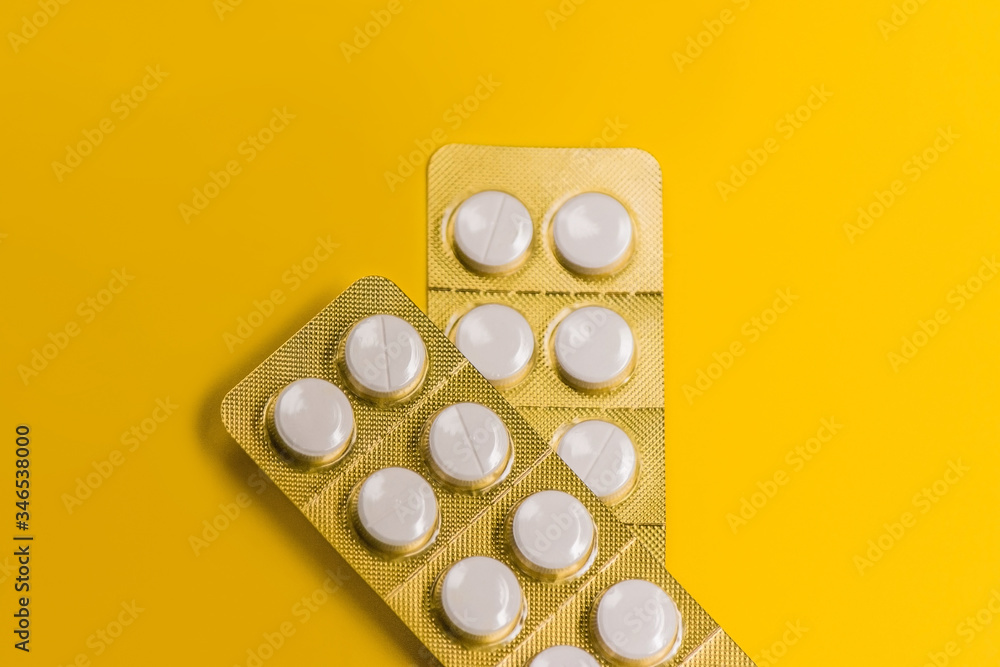 two sealed packages of white pills in yellow background
