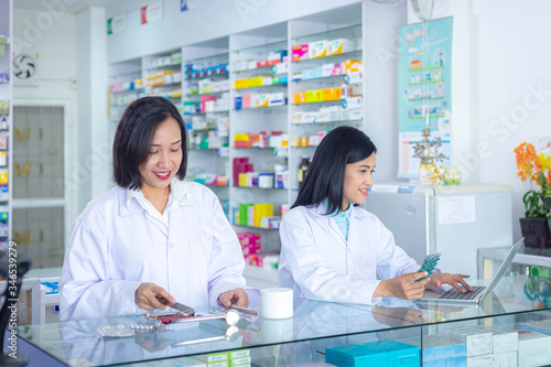 Two Asian pharmacists working in a pharmacy drugstore. Health care and medical concept.