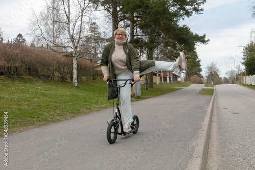 A woman riding a scooter on the road. Spring day