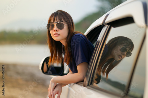 ํYoung Asian woman wearing sun glasses out of white SUV car window at the riverside, Travel car in vacation