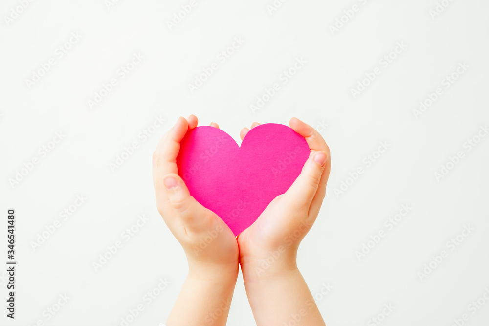 Paper pink heart in hands of child on white background. Child love concept. Paper pink heart in hands of child on white background. Child love concept.
