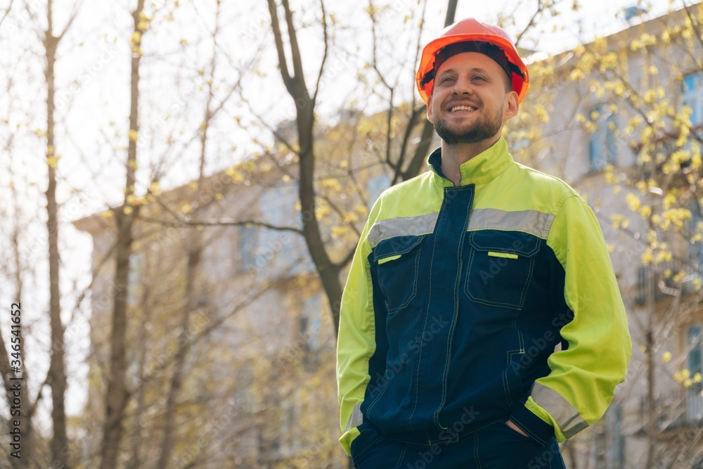 European man smiles in special clothes. The builder is glad that the work is over. apartment building concept European man smiles in special clothes. The builder is glad that the work is over. apartment building concept