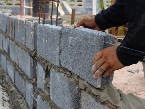Construction workers are building cement walls with brick blocks.