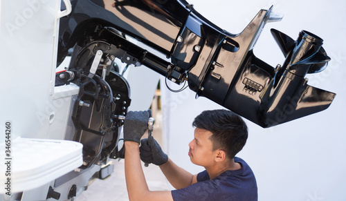 Mechanic is installing speed boat engine , a new engine on an aluminum boat.