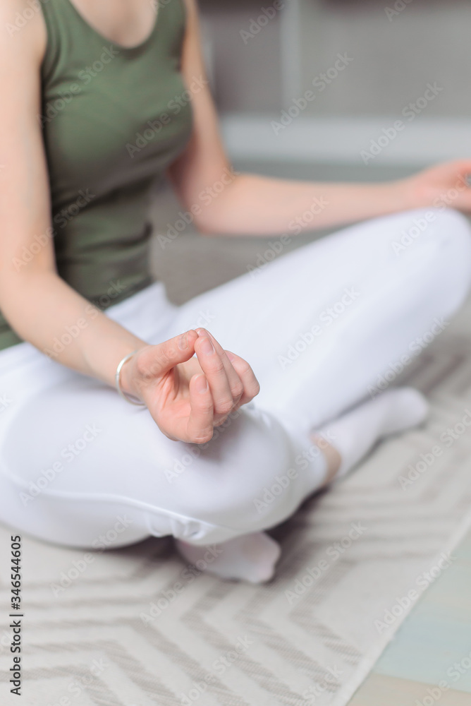 The girl is engaged in sports at home. A young woman in sports uniform does yoga exercises. Lotus pose, meditation. Close up hand mudra. The girl is engaged in sports at home. A young woman in sports uniform does yoga exercises. Lotus pose, meditation. Close up hand mudra.