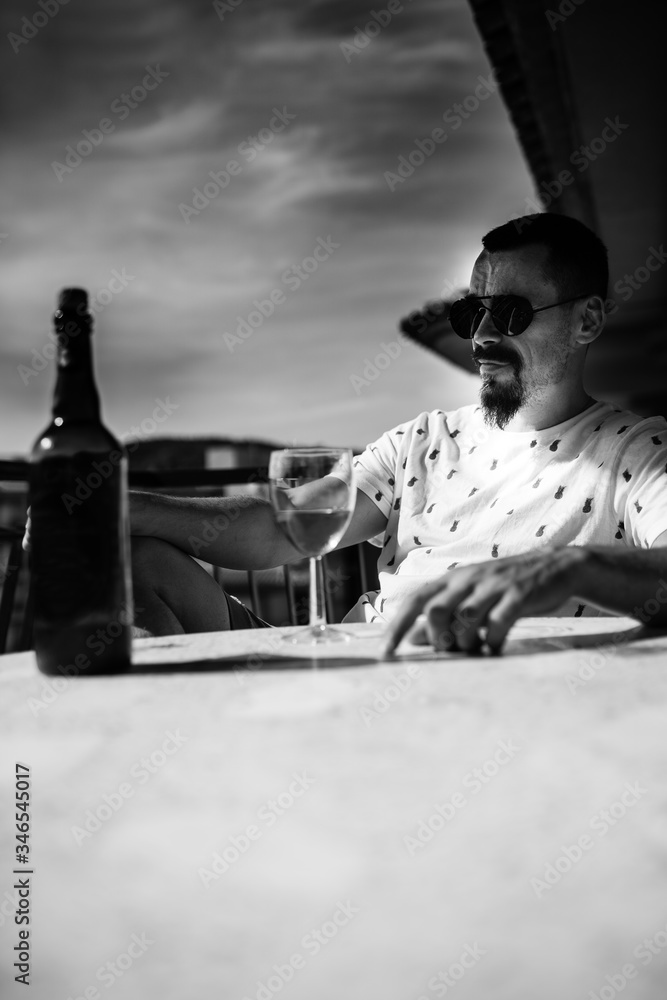 a man on the balcony is sitting at a table with a glass