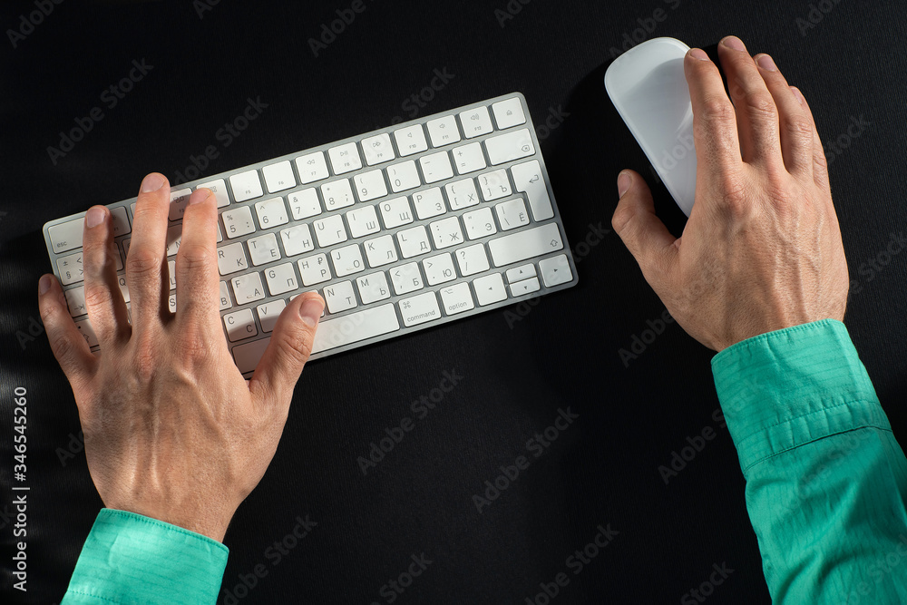 close-up of male hands, keyboard and mouse on a black table