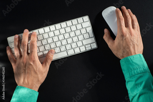 Obraz na płótnie close-up of male hands, keyboard and mouse on a black table w salonie