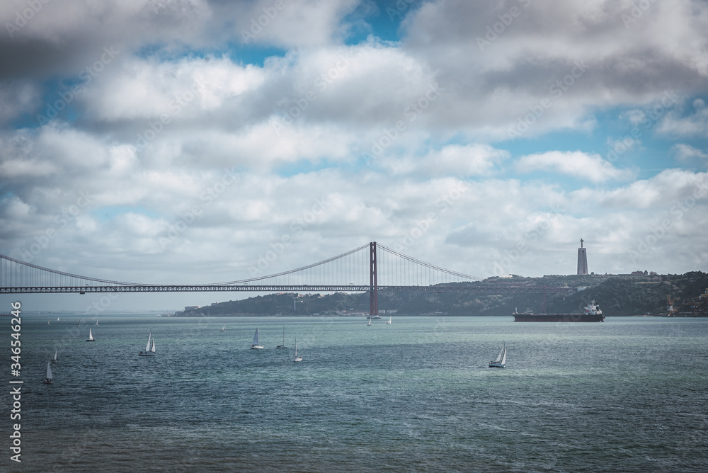 25th April bridge surrounded by boats with Christ behind in Lisbon