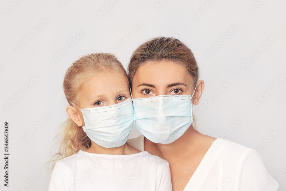 Family mother and daughter in medical masks together on an isolated background