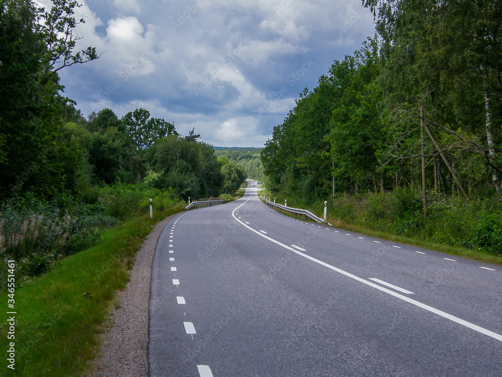 A panorama of a country road through forest landscape in Sweden