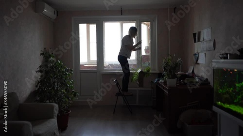 a woman removes potted flowers from a window and washes a window. A child is running next to her. Faster shooti photo