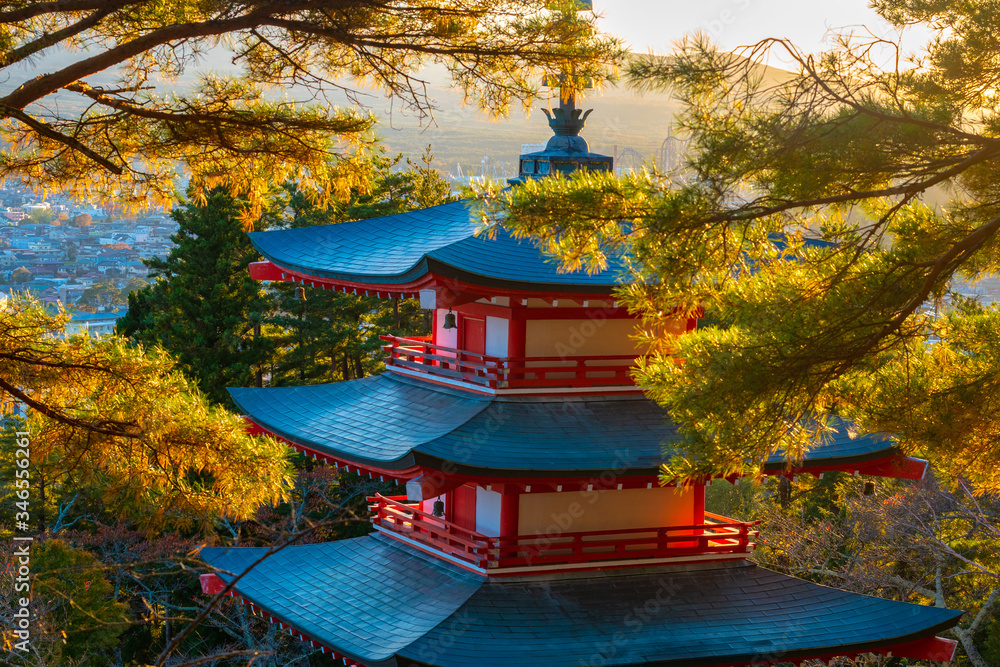 Fototapeta premium Japan. Scenery of the city of Fujiyoshida. Buddhist pagoda in the middle of autumn trees. Top of the Japanese pagoda close-up. Pagoda on the background of the city of Fujiyoshida. Tour of Japan.