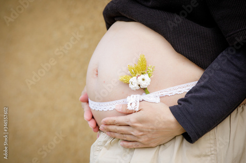 リボンを巻いて小さな花を添えた妊婦さんのお腹クローズアップ Stock Photo Adobe Stock リボンを巻いて小さな花を添えた妊婦さんのお腹クローズアップ Stock Photo Adobe Stock
