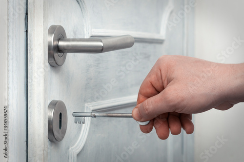 Caucasian man open a modern door with metal handle using an old rusty key
