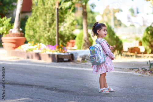 Cute child back to preschool with holographic backpack. Toddler kid first day at kindergarten. Happy sweet girl going back to school after covid-19, coronavirus quarantine and lockdown.