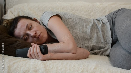 Young woman sleeping on a sofa with a TV remote control