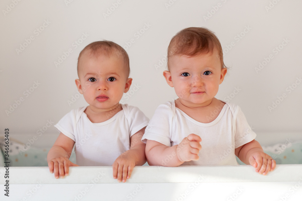 Fraternal twins sisters standing in crib Fraternal twins sisters standing in crib
