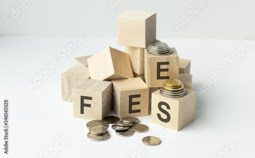 Coin stack and wooden blocks with the fee text. Fee Finance and Money concept. photo