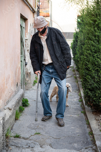 Man in protective mask with a cane walking with a dog © vbaleha