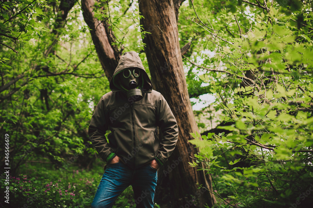 The man in the mask is hiding from the virus in the forest. Coronavirus is everywhere.