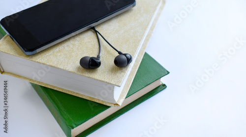  Close up earphones, tablet on stack of books. Listening to book. Audio book concept. Online education or entertainment. Copyspace.