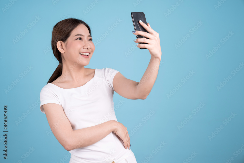 Portrait of an Asian woman taking a photo or video call with a friend, Isolated on a blue background. Portrait of an Asian woman taking a photo or video call with a friend, Isolated on a blue background.
