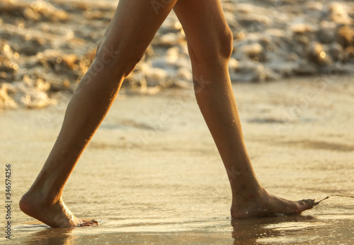 Legs of a girl on the seashore at sunset.