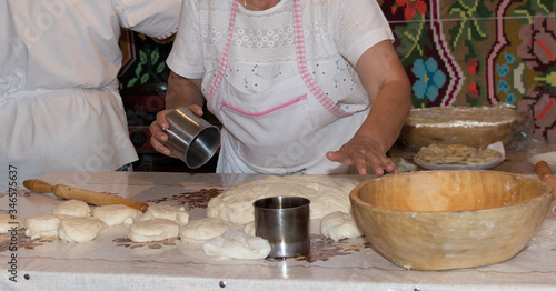 Traditional east european woman in authentic clothing kneading bread dough for 