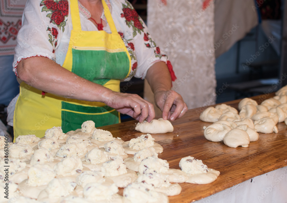 Traditional east european woman in authentic clothing kneading bread dough for 