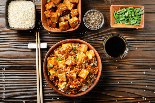 Flat lay view at traditional Chinese food mapo tofu dish with pork chives steamed rice soy sauce and spices closeup