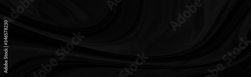 Black gray satin dark fabric texture luxurious shiny that is abstract silk cloth panorama background with patterns soft waves blur beautiful.