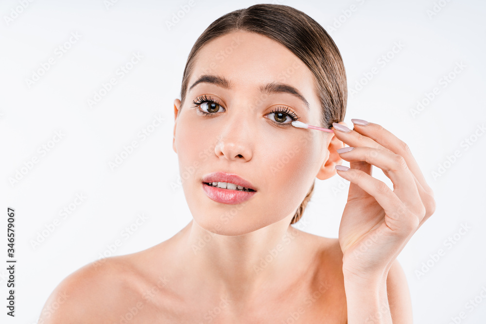 Beauty portrait of young woman removing make up with cotton swab isolated over white background