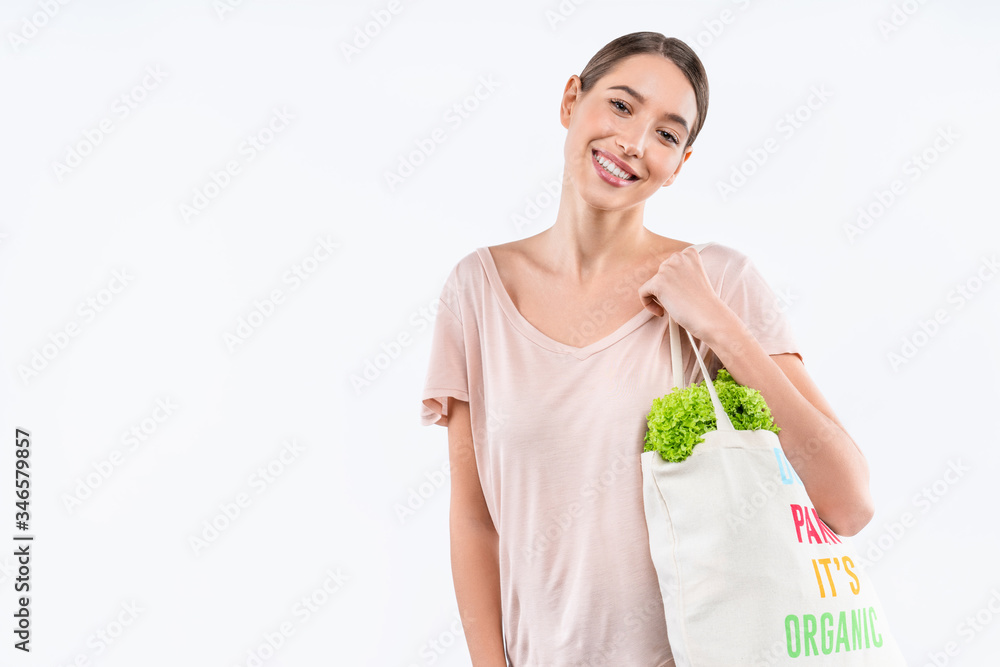Portrait of happy young woman holding grocery bag with organic food over white background Portrait of happy young woman holding grocery bag with organic food over white background