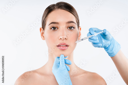 Close up of beautiful woman gets injection in her lips isolated over white background