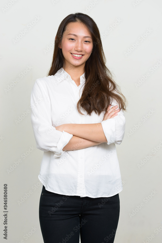 Portrait of happy young beautiful Asian businesswoman smiling with arms crossed Portrait of happy young beautiful Asian businesswoman smiling with arms crossed