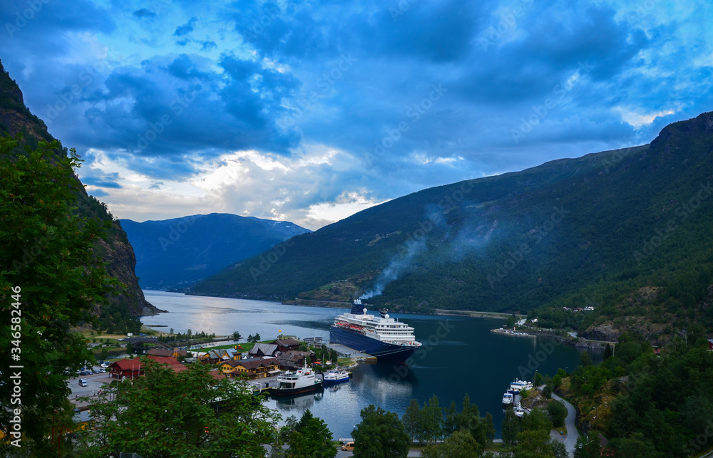 Cruise ship in the marina of famous norwegian village Flam in sea harbor with green mountains. Beautiful Nature Norway natural landscape on fjord Sognefjord.