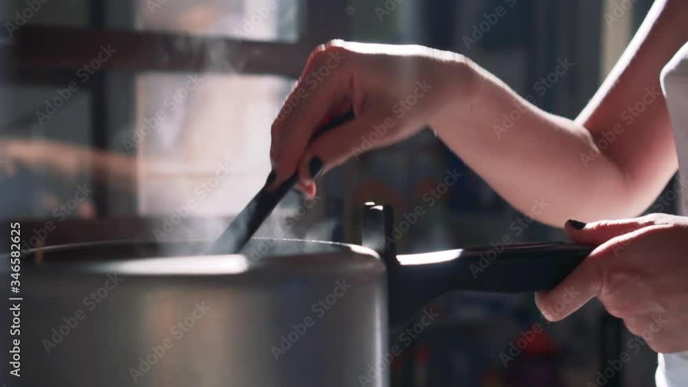 Woman hand stirring food in the pan coming out of smoke. Selective focus. Woman hand stirring food in the pan coming out of smoke. Selective focus.