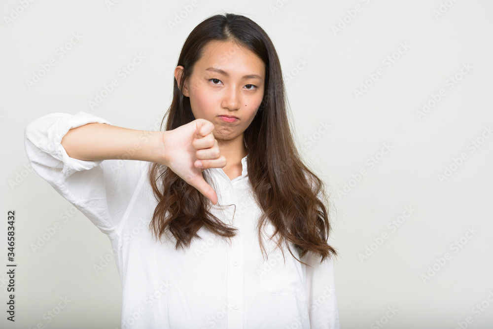 Portrait of young Asian businesswoman giving thumbs down Portrait of young Asian businesswoman giving thumbs down