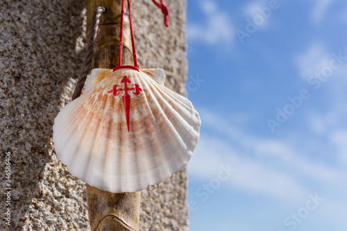 Obraz na płótnie Walking stick and seashell of the Camino de Santiago leaning on granite stone wall