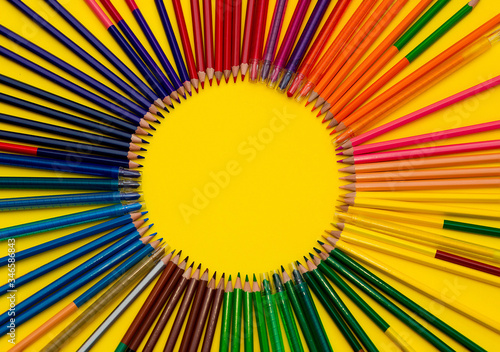 A lot of multi-colored pencils in a circle on a black bright background. School life concept