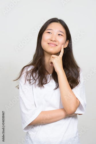 Portrait of young beautiful Asian woman thinking