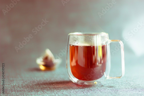 Glass transparent Cup with double walls and brewed tea and a bag in the Cup. Toned. Copy space