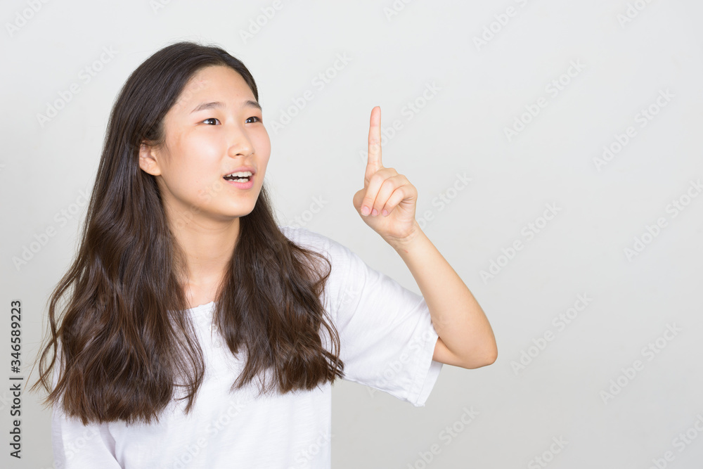 Portrait of happy young beautiful Asian woman pointing up Portrait of happy young beautiful Asian woman pointing up