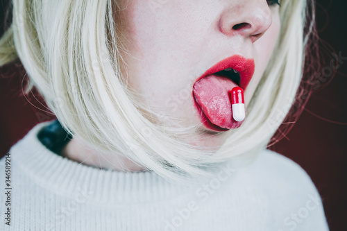 Conceptual image about drug addict with a pill in a young woman tongue photo