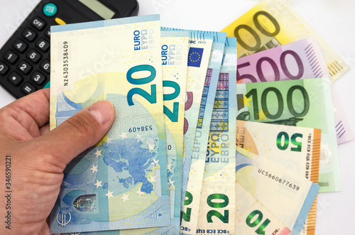 20 euros in hand on the background of banknotes and a calculator. White background. Much money. To count money. Close-up.