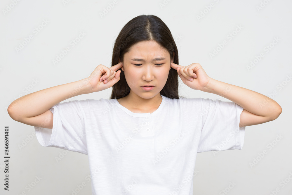 Portrait of stressed young Asian woman covering ears Portrait of stressed young Asian woman covering ears